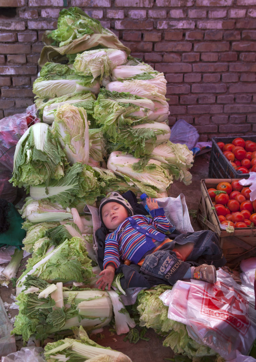 Baby Sleeping In The Vegetables, Opal Village Market, Xinjiang Uyghur Autonomous Region, China