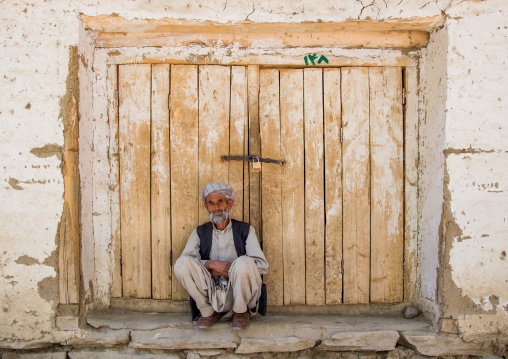 Old man in front of a closed door in the market, Badakhshan province, Ishkashim, Afghanistan