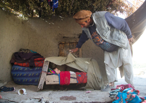 Father looking at his baby sleeping in a craddle, Badakhshan province, Qazi deh, Afghanistan