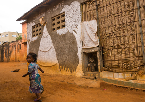 Benin, West Africa, Porto-Novo, young girl passing in front of zangbeto adiye temple