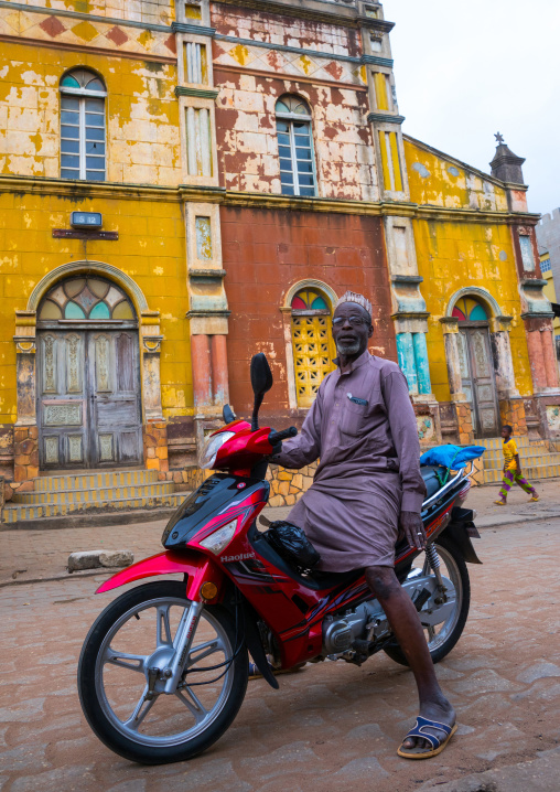 Benin, West Africa, Porto-Novo, old muslim man on a scooter in front of the multicoloured great mosque