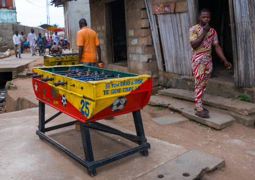 Benin, West Africa, Porto-Novo, men passing in front of a table football babyfoot in the street