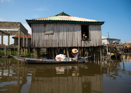 Benin, West Africa, Ganvié, boat passing in front of the stilt house on lake nokoue