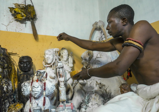 Benin, West Africa, Bonhicon, kagbanon bebe voodoo priest putting some oil on the statues during a ceremony