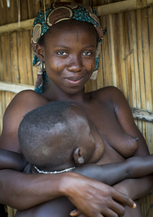 Benin, West Africa, Onigbolo Isaba, holi tribe woman covered with traditional facial tattoos and scars holding her baby
