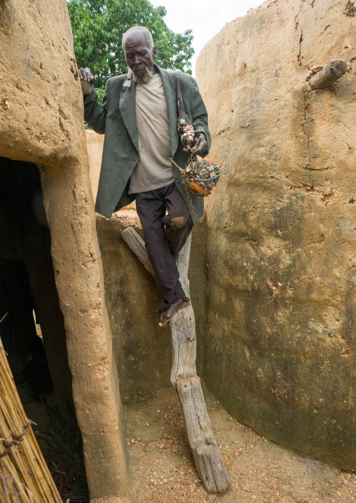 Benin, West Africa, Boukoumbé, man climbing a ladder in a traditional tata somba house