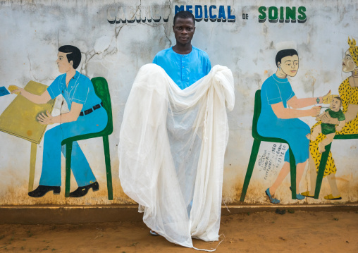 Benin, West Africa, Bopa, doctor holding a mosquito net in front of a wall painting