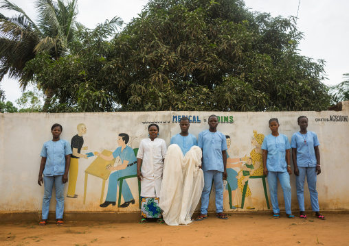 Benin, West Africa, Bopa, doctor and nurses holding a mosquito net in front of a wall painting