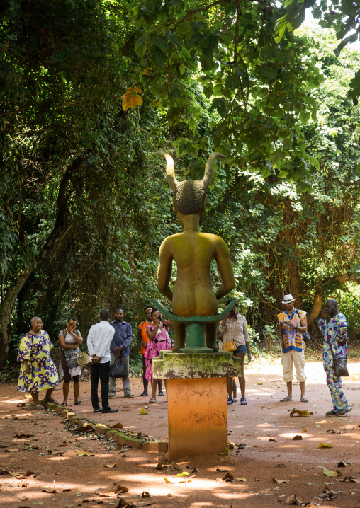Benin, West Africa, Ouidah, tourists looking at horned deity figure in kpasse sacred forest
