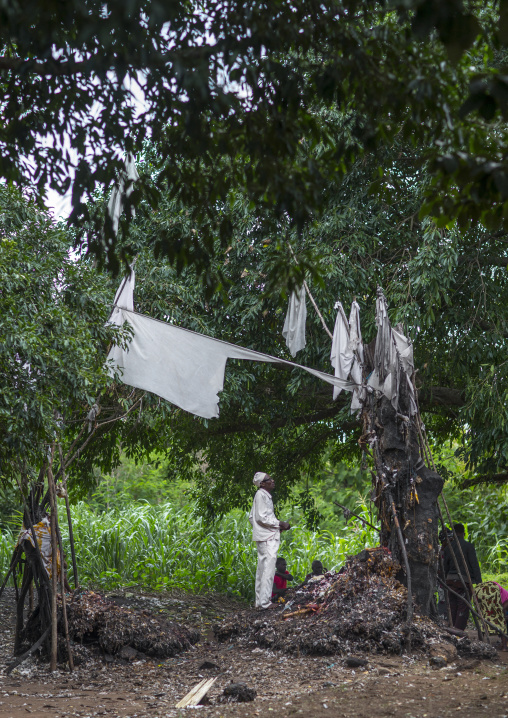Benin, West Africa, Dankoly, a priest with a coca cola bottle praying on a voodoo shrine
