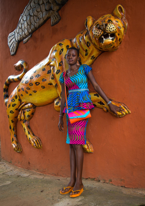 Benin, West Africa, Savalou, young woman pausing in front of the royal palace sponsored by muammar gaddafi