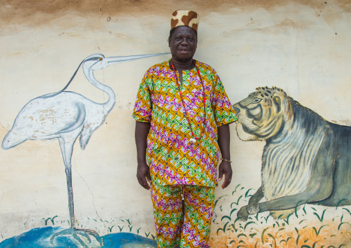 Benin, West Africa, Savalou, a priest from the voodoo covent of the royal palace in front of a painted wall