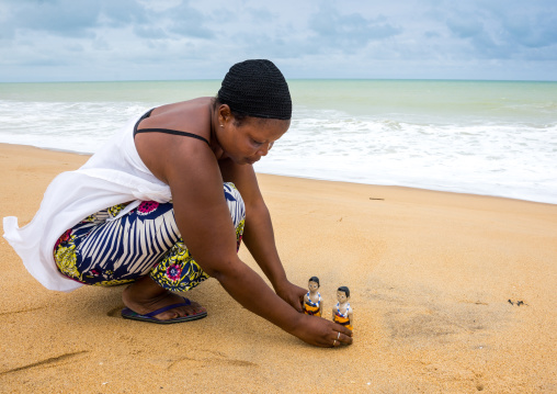 Benin, West Africa, Ouidah, mrs kpsouayo carrying the carved wooden figures made to house the soul of her dead twins on the beach