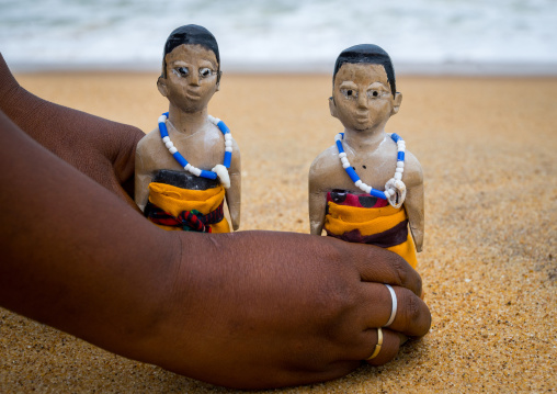 Benin, West Africa, Ouidah, mrs kpsouayo carrying the carved wooden figures made to house the soul of her dead twins on the beach
