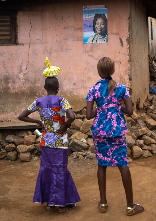 Benin, West Africa, Savalou, two women looking a poster on a wall
