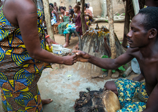 Benin, West Africa, Bopa, woman giving alcohol to a drummer during a voodoo ceremony