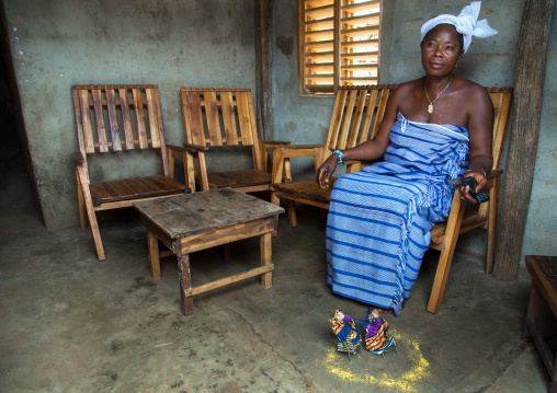 Benin, West Africa, Bopa, miss hounyoga resting with the carved wooden figures made to house the soul of her dead twins