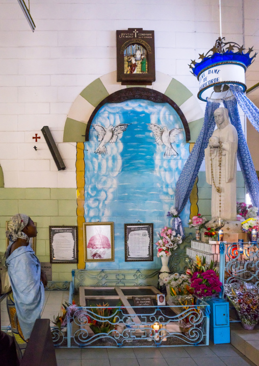 Benin, West Africa, Cotonou, woman praying inside the notre dame roman catholic cathedral