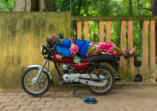 Benin, West Africa, Porto-Novo, man sleeping on top of motor bike