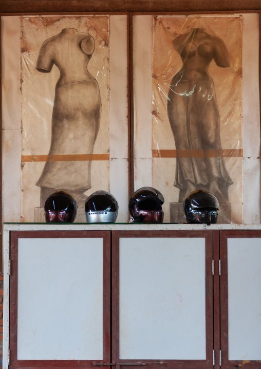 Helmets below drawings of khmer statues in a school, Battambang province, Battambang, Cambodia