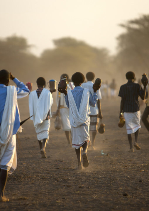 Rear View Of A Group Of Karrayyu Tribe Men In White Wrap Around Clothes Bringing Gifts For The Gadaaa Ceremony At Dawn, Metehara, Ethiopia