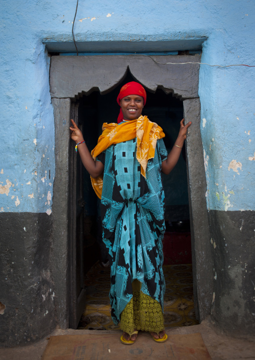Portrait Of A Woman With Toothy Smile At The Entrance Of Her Blue-painted House, Harar, Ethiopia