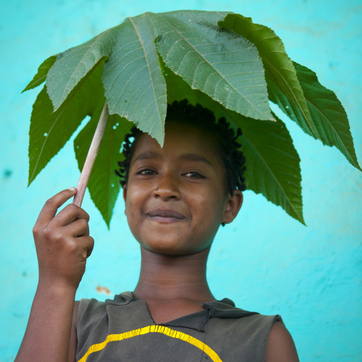 Young ara boy portrait with leaf made umbrella omo valley Ethiopia
