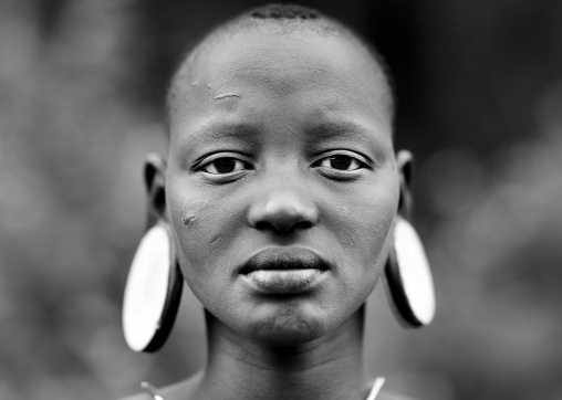 Portrait Of A Young Mursi Shaved Head Girl With Clay Plate In Ears In Jinka Omo Valley Ethiopia