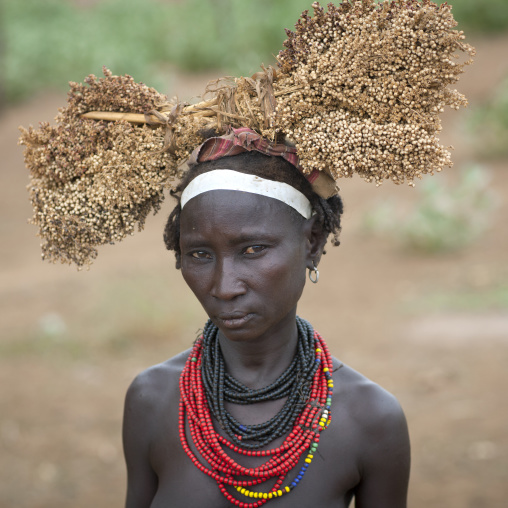 Dassanech Young Woman Wearing Beaded Necklaces And Holding Dried Plants On Her Head  Omo Valley Ethiopia