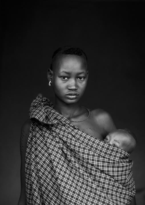 Portrait Of A Bodi Tribe Mother Carrying Her Baby, Hana Mursi, Omo Valley, Ethiopia