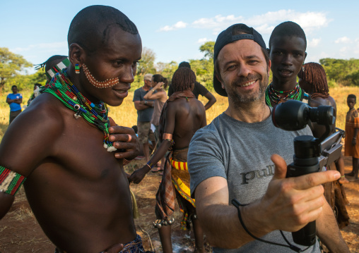 European tourist showing the screen of his camera to hamer tribe people, Omo valley, Turmi, Ethiopia