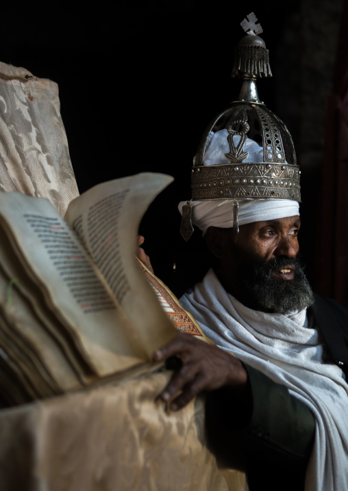 Ethiopian orthodox priest with an old bible in nakuto lab rock church, Amhara region, Lalibela, Ethiopia
