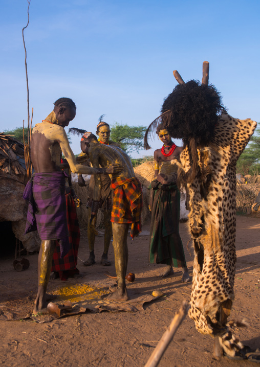 A dassanech man puts some mud on his friend body to join the dimi ceremony, Omo valley, Omorate, Ethiopia