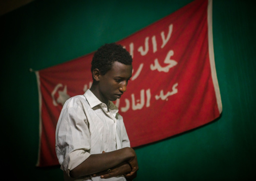 Sufi man worshipper in front of islamic red flag, Harari region, Harar, Ethiopia