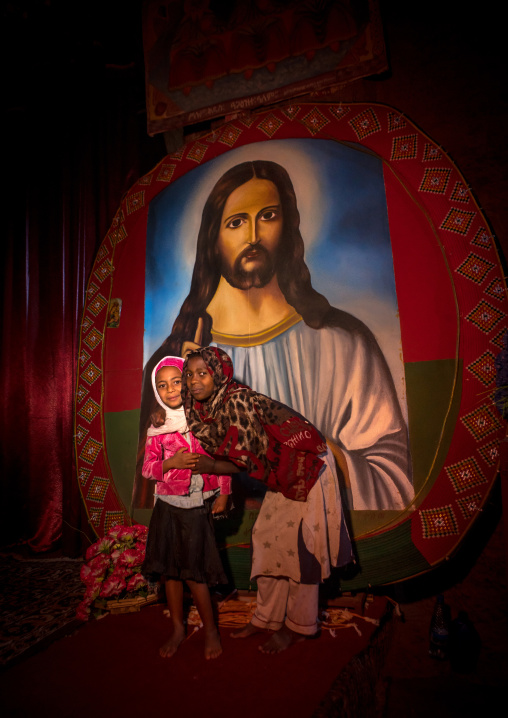 Children in medhane alem rock church in front of a huge painting of jesus, Amhara region, Lalibela, Ethiopia