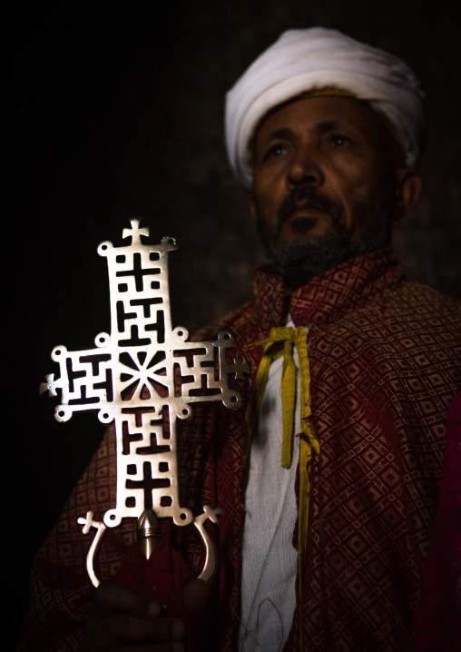 Ethiopian orthodox priest holding a cross inside a rock church, Amhara region, Lalibela, Ethiopia