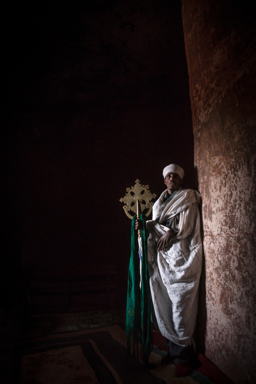 Ethiopian orthodox priest holding a cross inside a rock church, Amhara region, Lalibela, Ethiopia