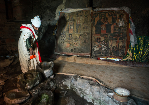 Ethiopian orthodox priest collecting holy water in nakuto lab rock church, Amhara region, Lalibela, Ethiopia