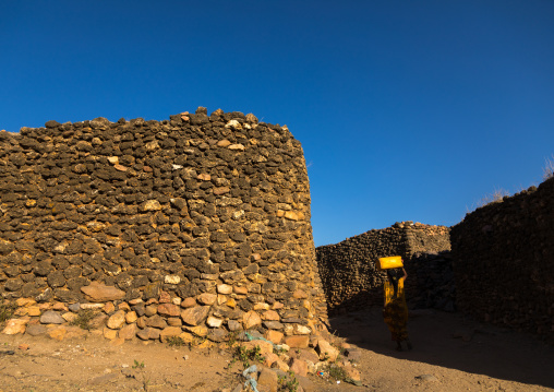 Argoba woman carrying water in jericans in a traditional stone houses cliff-top village, Harari Region, Koremi, Ethiopia
