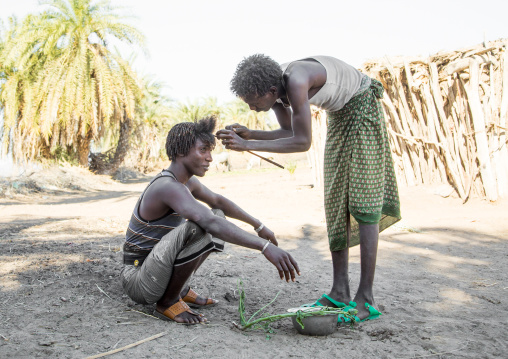 Afar man having a traditional hairstyle with a stick to make curly hair, Afar region, Afambo, Ethiopia