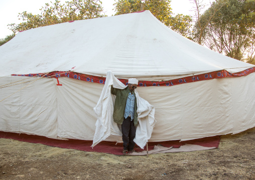 Ethiopian orthodox priest in front of a giant tent putting his traditional shawl during Timkat epiphany festival, Amhara region, Lalibela, Ethiopia