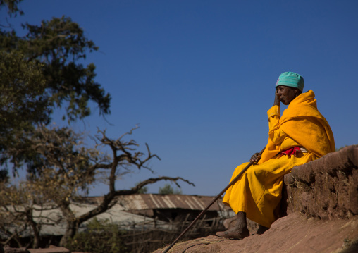 Lonely ethiopian monk woman in yellow shawl, Amhara region, Lalibela, Ethiopia