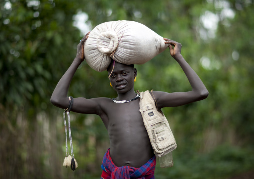 Young menit man carrying a sack on his head, Tum market, Omo valley, Ethiopia