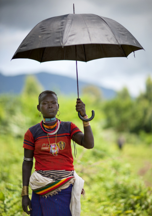 Menit woman sheltering under her umbrella, Tum market, Omo valley, Ethiopia