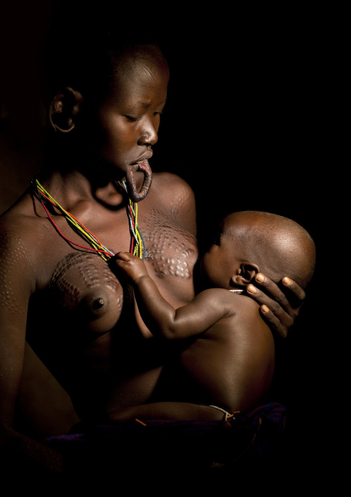 Suri Woman With Stretched Lip Breast Feeding Her Baby, Turgit Village, Omo Valley, Ethiopia