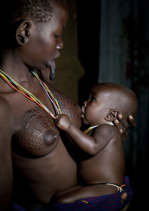 Suri Woman With Stretched Lip Breast Feeding Her Baby, Turgit Village, Omo Valley, Ethiopia