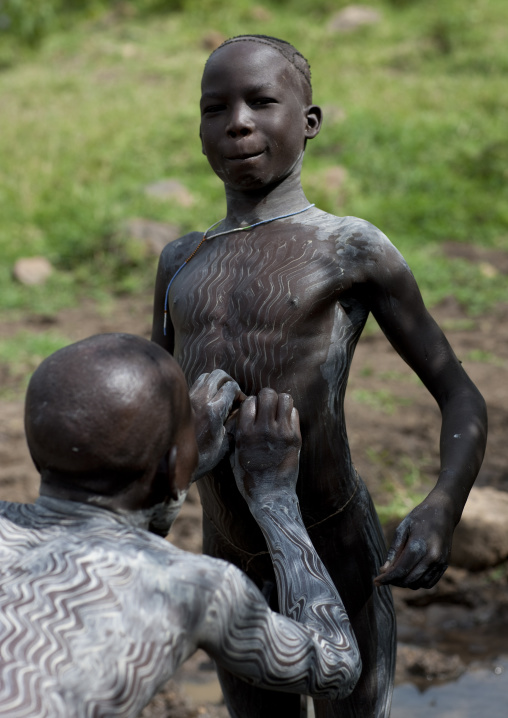 Clay body paintings on Suri warriors before donga stick fighting, Turgit village, Omo valley, Ethiopia