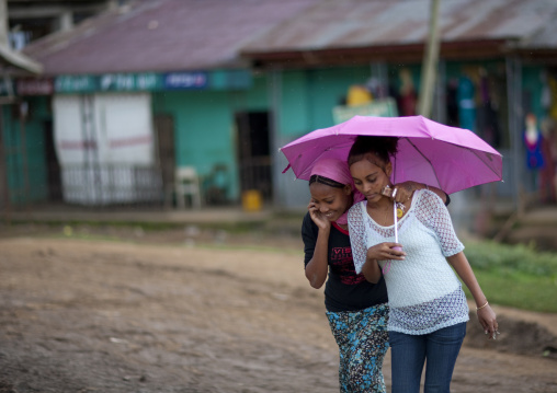 Teenager girls sheltering under an umbrella, Ethiopia