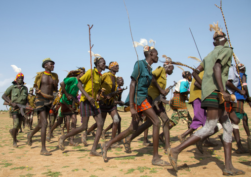 Men running in line with weapons during the proud ox ceremony in the Dassanech tribe, Turkana County, Omorate, Ethiopia