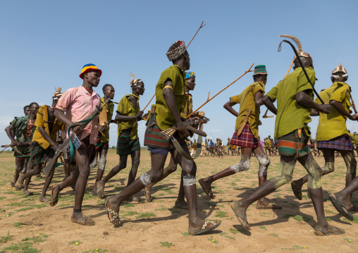 Men running in line with weapons during the proud ox ceremony in the Dassanech tribe, Turkana County, Omorate, Ethiopia
